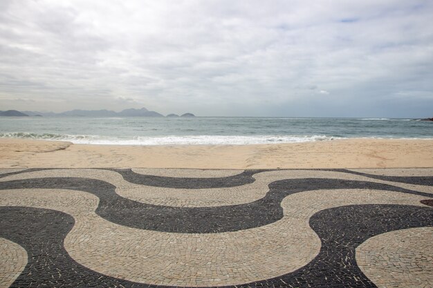 Foto calçadão clássico de copacabana com a praia ao fundo no rio de janeiro