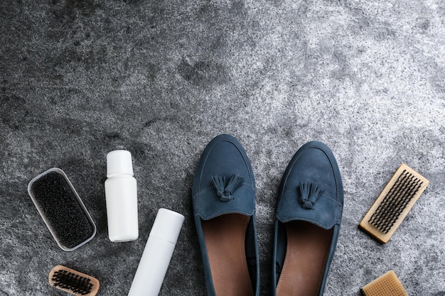 Foto calçado estiloso com acessórios para cuidar de sapatos em mesa de pedra cinza plana espaço para texto