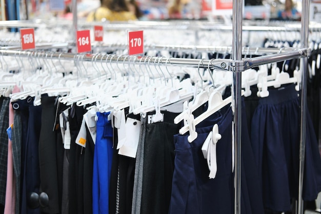 Calças infantis estão penduradas em cabides em um shopping center como parte de um uniforme escolar Foto horizontal