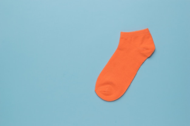 Un calcetín deportivo naranja sobre fondo azul. Endecha plana.