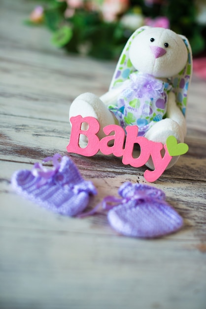 Calcetines de bebé de punto morado con la inscripción de un niño y una liebre de juguete sobre un fondo de madera.