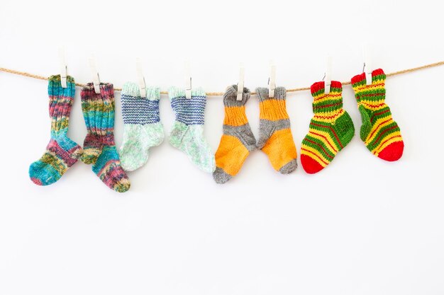 Calcetines de varios colores colgando de la cuerda de la ropa contra un fondo blanco