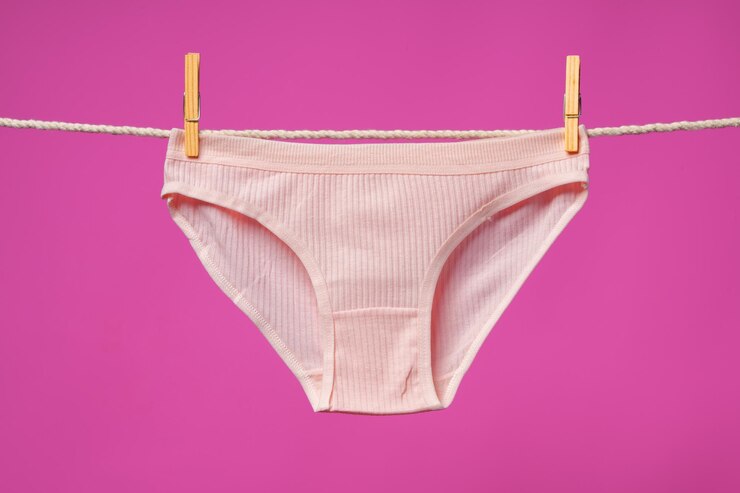 Foto calcinha feminina pendurada na corda contra fundo de estúdio rosa