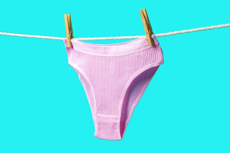 Foto calcinhas femininas penduradas em corda contra o fundo azul do estúdio