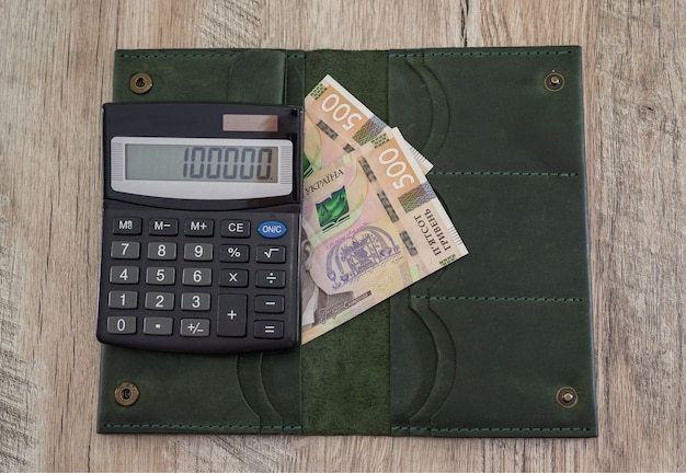 Calculadora y billetera femenina 500 hryvnia en una mesa de madera. Concepto financiero.