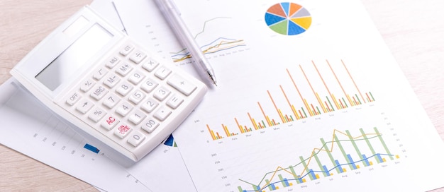 Calculadora blanca e informe con gráfico y concepto de gráfico de beneficio financiero anual resumen bancario e inversión macro de espacio de copia de primer plano