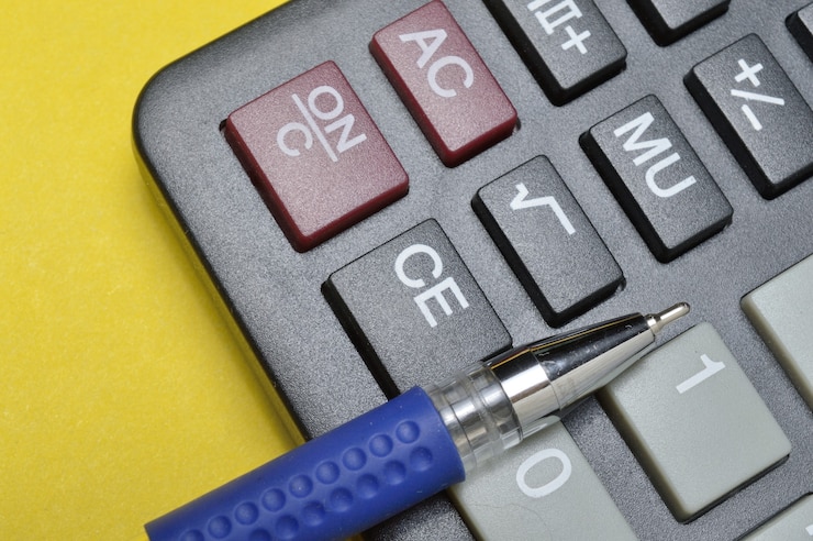 Foto la calculadora y el bolígrafo se encuentran sobre un fondo amarillo. de cerca.