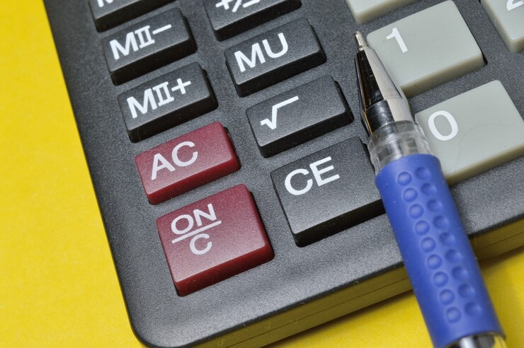 Foto la calculadora y el bolígrafo se encuentran sobre un fondo amarillo. de cerca.