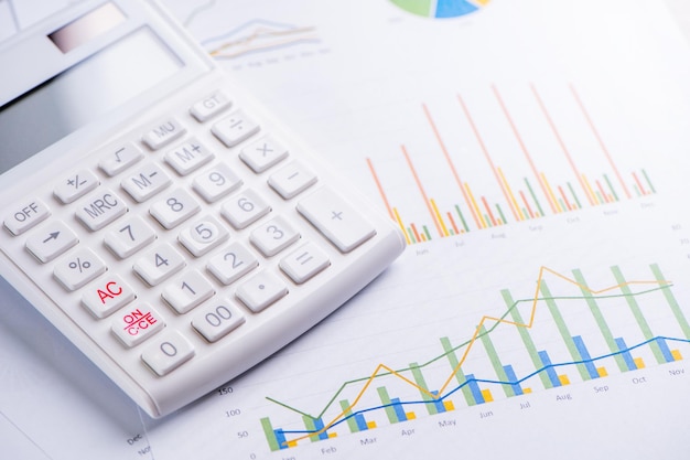 Calculadora branca e relatório com conceito de gráfico e gráfico de visão geral de lucro financeiro anual bancário e investimento fechando macro de espaço de cópia