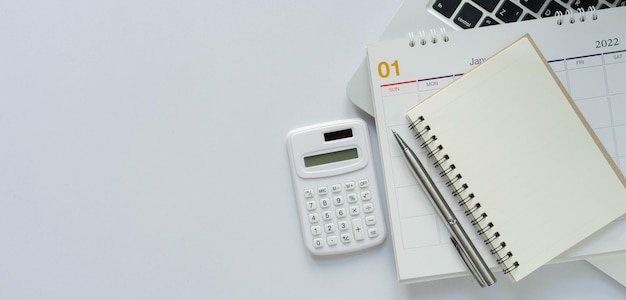 Calculadora con calendario portátil y material de oficina portátil sobre fondo de color blanco