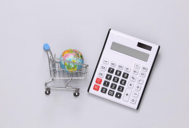 Calculadora y carrito de compras con globo sobre fondo gris Vista superior