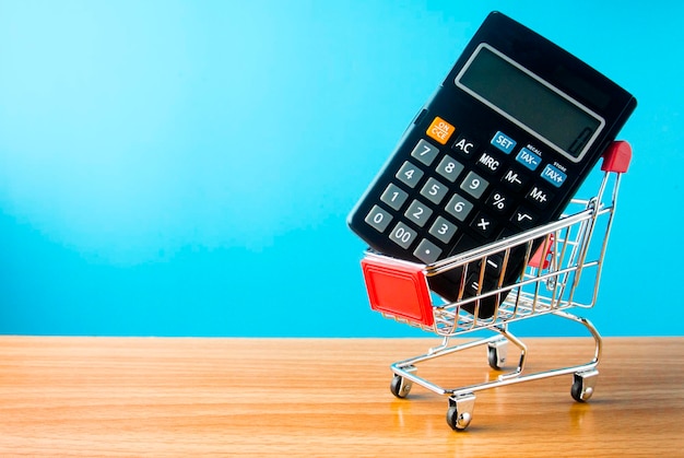 Calculadora en el carrito de compras en la mesa contra un fondo azul