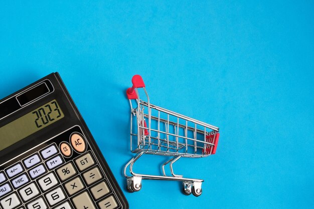 Calculadora y carrito de compras sobre fondo azul Concepto de compras y compras de comestibles