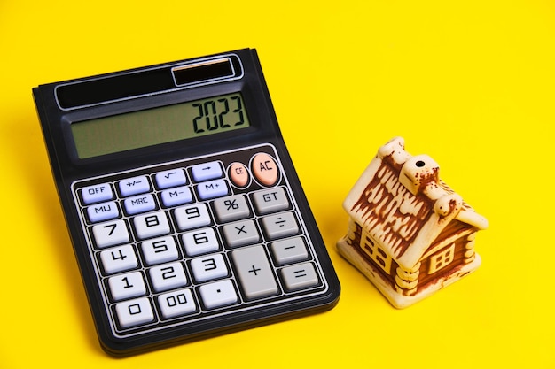 Calculadora y casa sobre un fondo amarillo concepto hipoteca compra y venta de vivienda