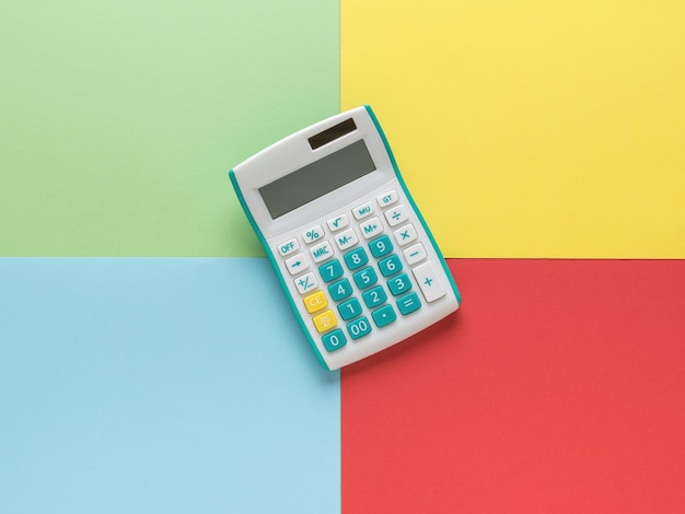 Una calculadora clásica sobre un fondo de cuatro colores. Un dispositivo para la computación. Concepto mínimo de contabilidad.