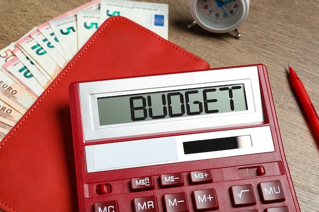 Calculadora com caderno de orçamento de palavras e dinheiro na mesa fechada