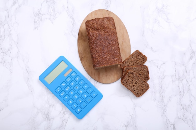 Calculadora com fatias de pão de centeio integral em fundo de mármore conceito de contagem de calorias de dieta