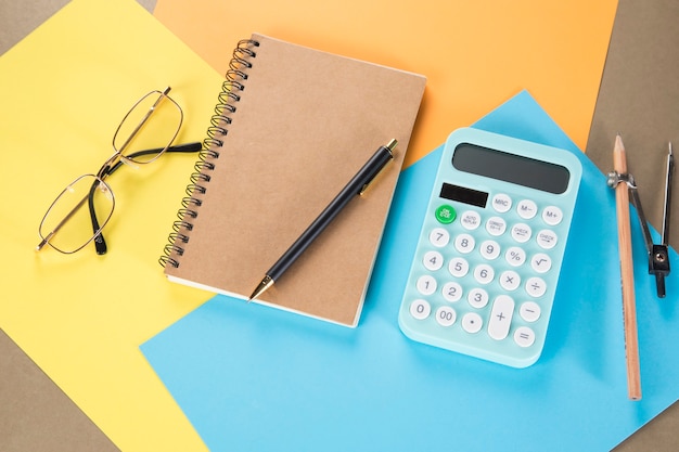 Calculadora y cuaderno en trozos de papel multicolores. concepto de escritorio