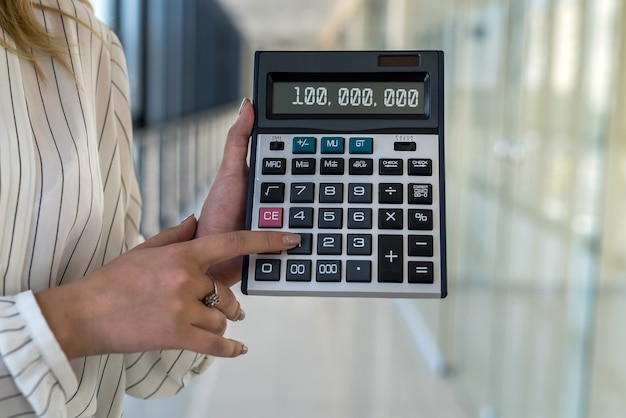 Calculadora de exploração de mão feminina no moderno centro de negócios. conceito de finanças