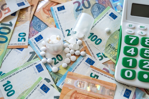 Calculadora de diferentes píldoras y billetes en euros. concepto médico. farmacia de alto costo