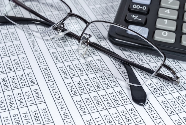 Calculadora e óculos no fundo de papéis financeiros