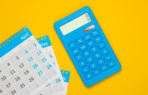 Calculadora con las hojas del calendario mensual en amarillo. Cálculo de pagos de alquiler de vivienda.