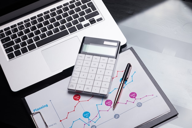 La calculadora moderna está en una computadora portátil y en una hoja con un gráfico