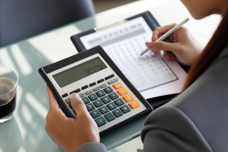 Calculadora na mão de uma mulher fazendo anotações em um conceito de contabilidade de notebook