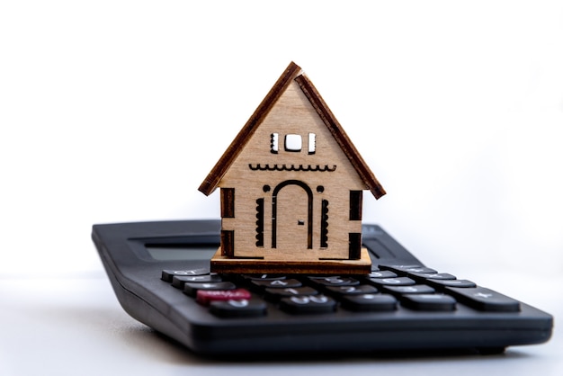 Calculadora na mesa com pequena casa. descreve o planejamento financeiro para investir ou comprar uma casa. planejamento de investimentos imobiliários, empréstimo à habitação, conceito de hipoteca.