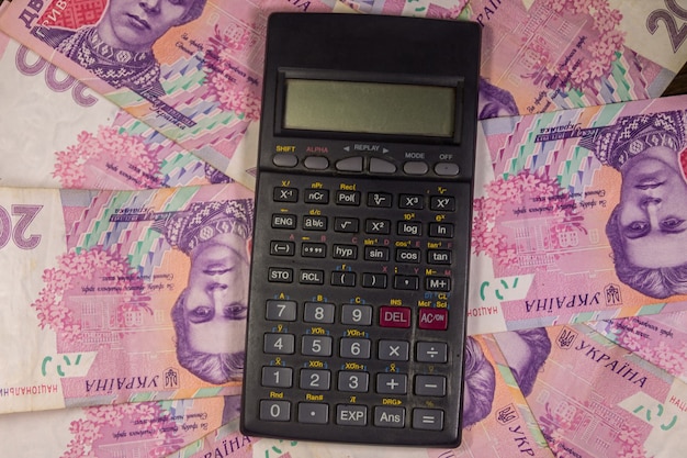 Calculadora preta com fundo de notas de duzentas hryvnia ucranianas