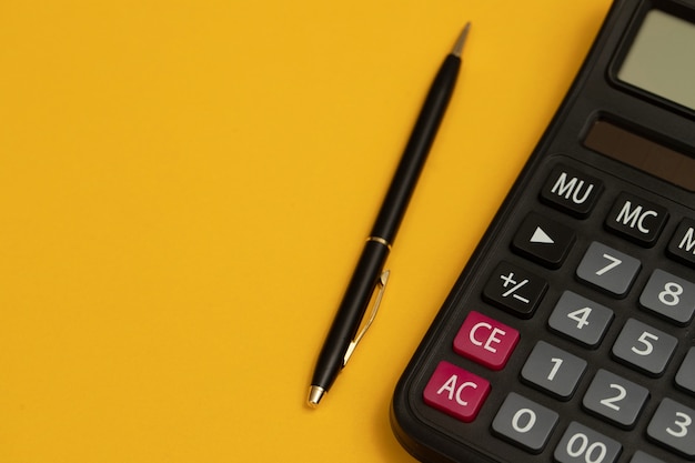 Calculadora pronta para trabalhar com caneta preta e fundo amarelo