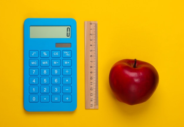 Calculadora y regla de madera, manzana en amarillo. Concepto de educación