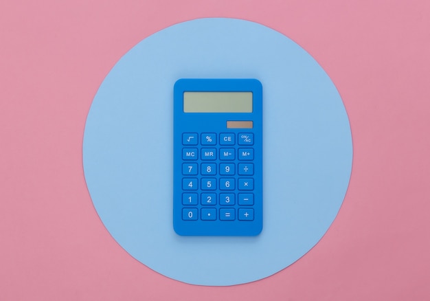 Calculadora sobre fondo rosa con un círculo azul. Foto de estudio conceptual. Minimalismo. Vista superior