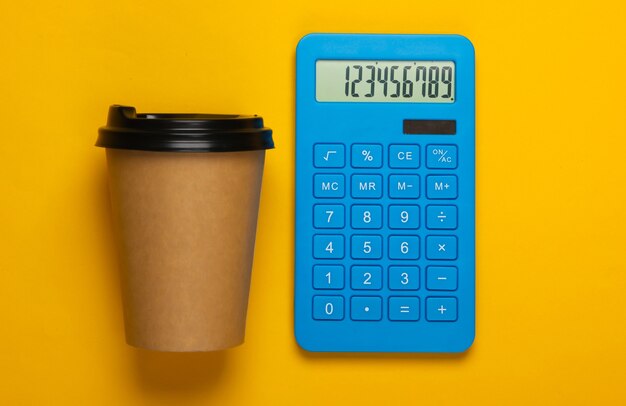 Calculadora con una taza de café de cartón en amarillo