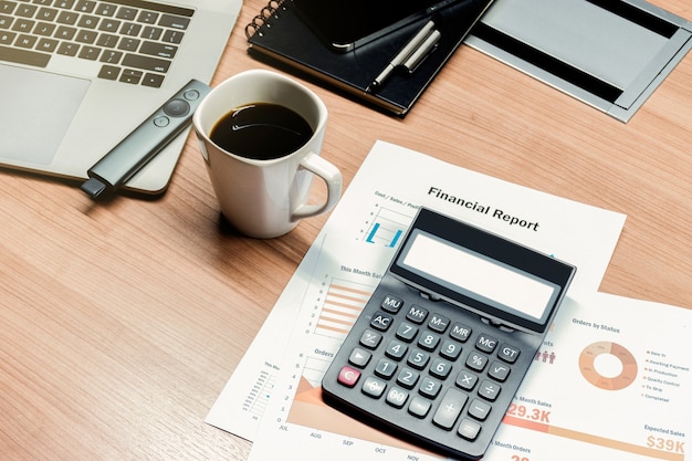 Calculadora de vista superior, papeleo, taza de café y computadora portátil en la mesa en la sala de reuniones