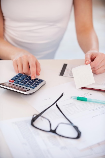 Calculando sus gastos. Imagen recortada de mujer calculando sus gastos mientras sostiene una factura