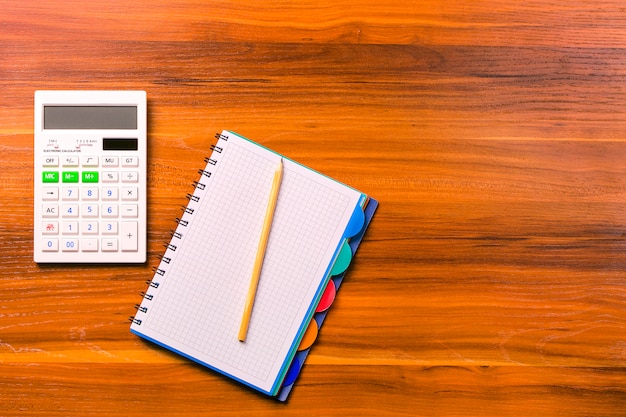 Calcular, caderno e lápis na mesa de madeira.