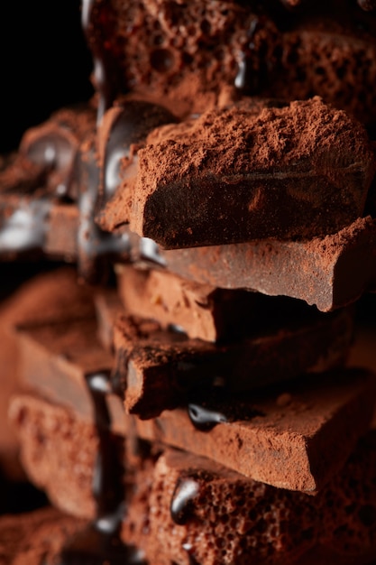 calda de chocolate sendo derramada em pedaços de chocolate amargo isolados no preto