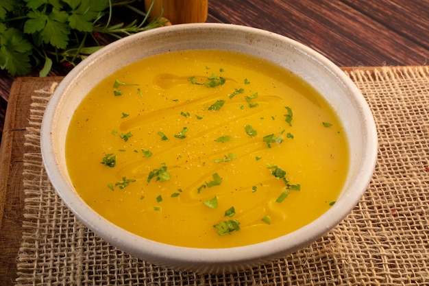 Caldo de crema de mandioca caliente en un tazón blanco sobre una mesa de madera