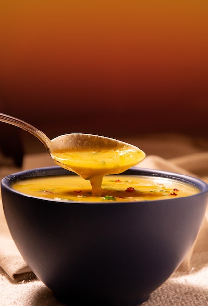 Caldo de creme de mandioca quente em uma tigela azul, sopa amarela, foto vertical, instagram, copie o espaço