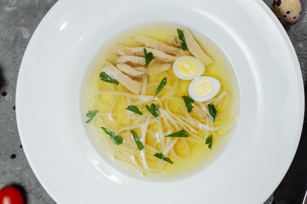 Foto caldo de frango com baixo teor de gordura com um ovo meio cozido e salsa em uma tigela de vidro isolada em fundo branco