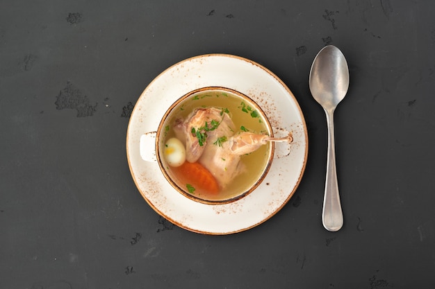 Caldo de galinha com metade de frango em uma tigela branca em cinza