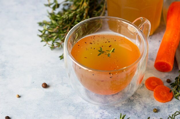 Caldo de osso caseiro em caneca de vidro e vegetais