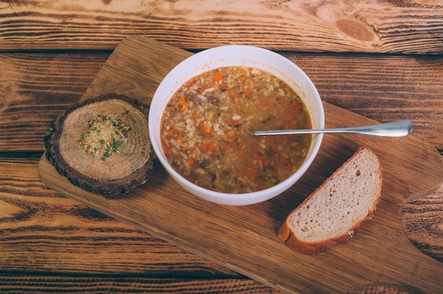 Caldo de sopa em uma tigela com pão sobre uma mesa de madeira.