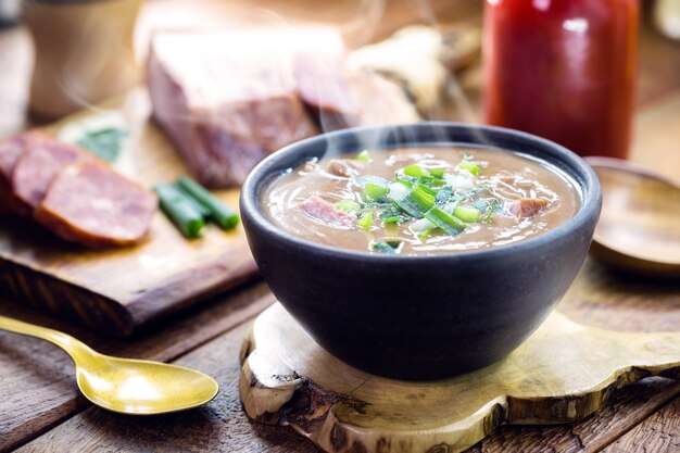 Caldo de frijoles brasileño, sopa de frijoles casera servida caliente en invierno, con ingredientes en el fondo