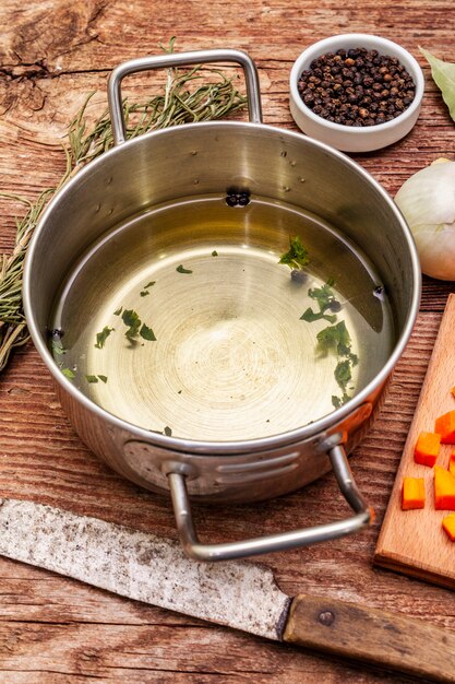 Caldo de pato transparente en sartén con ingredientes frescos