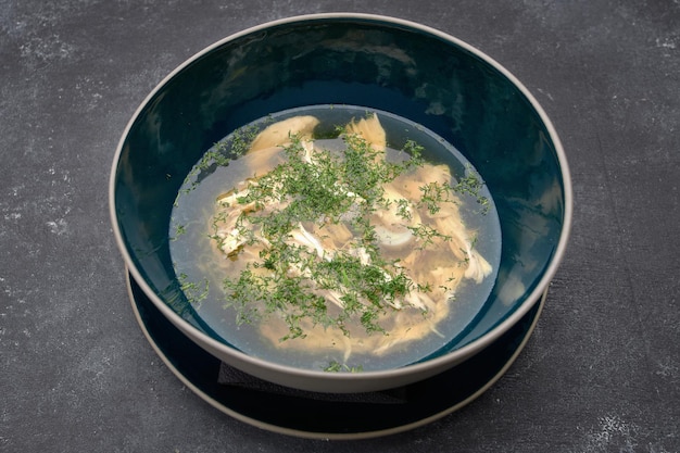 Caldo de pollo con consomé de eneldo sobre un fondo oscuro