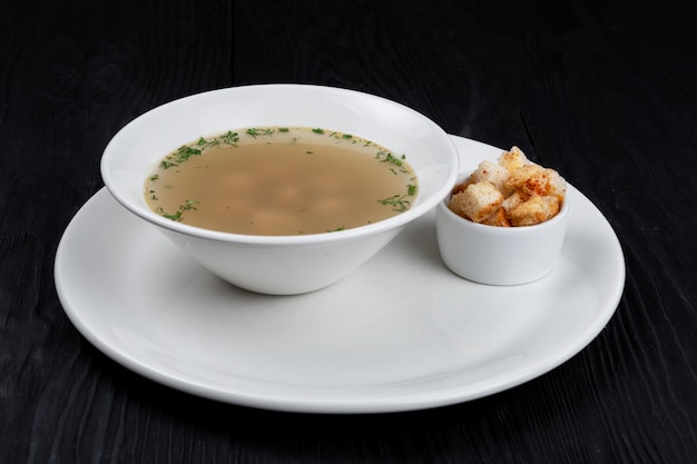 Caldo de pollo en un plato con albóndigas de pollo y picatostes