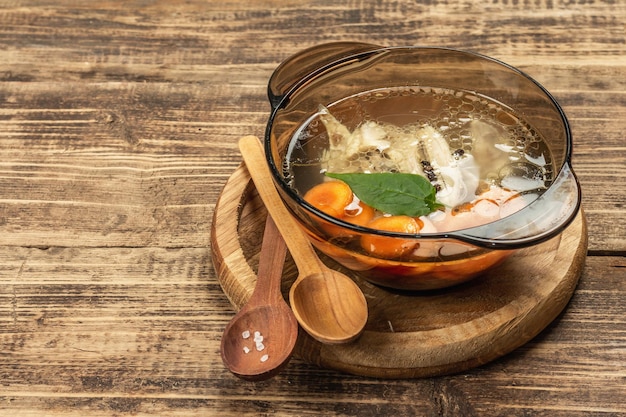 Caldo de pollo transparente. Sopa clara baja en grasas con zanahoria, verduras y especias. Plato caliente, cubiertos, fondo de madera vieja, espacio de copia