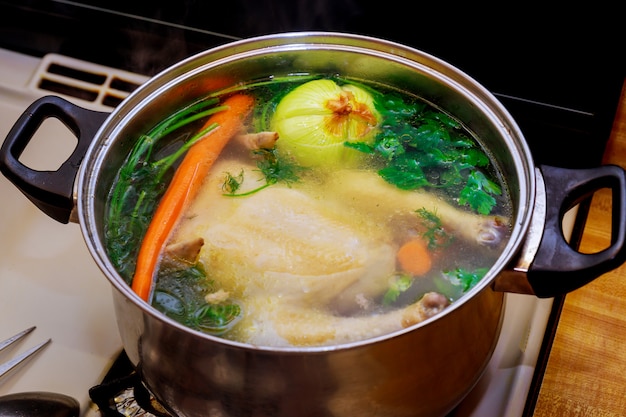 Caldo de pollo con zanahorias, pollo entero, cebolla, apio y perejil.